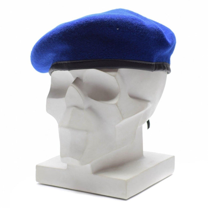 Véritable béret militaire allemand en laine bleu royal sur tête de mannequin blanche avec bande de garniture en cuir noir.