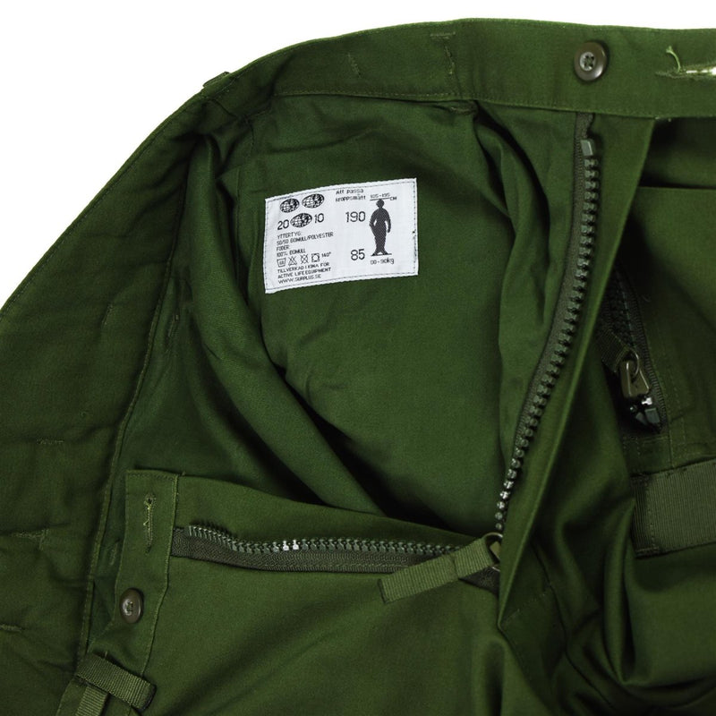 Close-up of genuine Swedish thermal tanker pants in olive green showing zipper, button, and inner label details