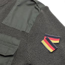 Close-up of olive green Mil-Tec German Bundeswehr wool sweater with fabric pocket and German flag patch on sleeve.