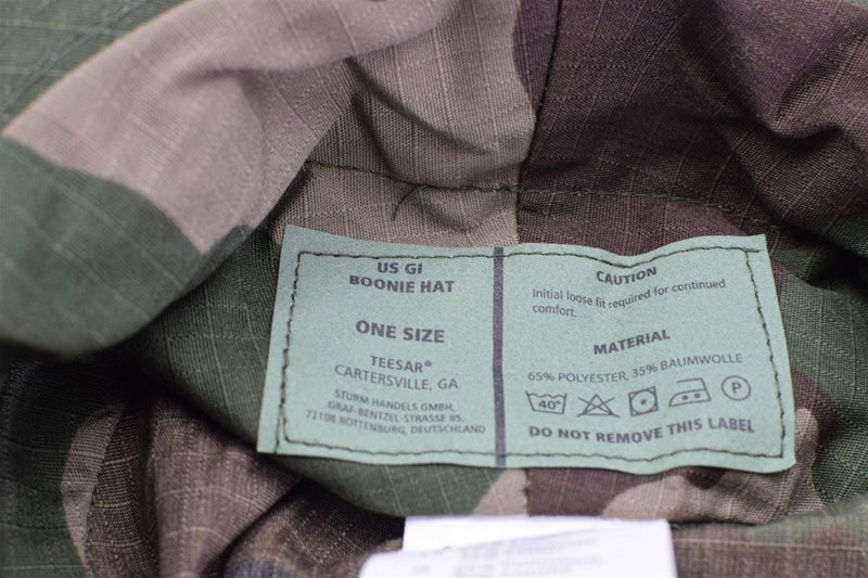 Close-up of Mil-Tec US GI boonie hat label showing size, material, and care instructions on CCE camo fabric.