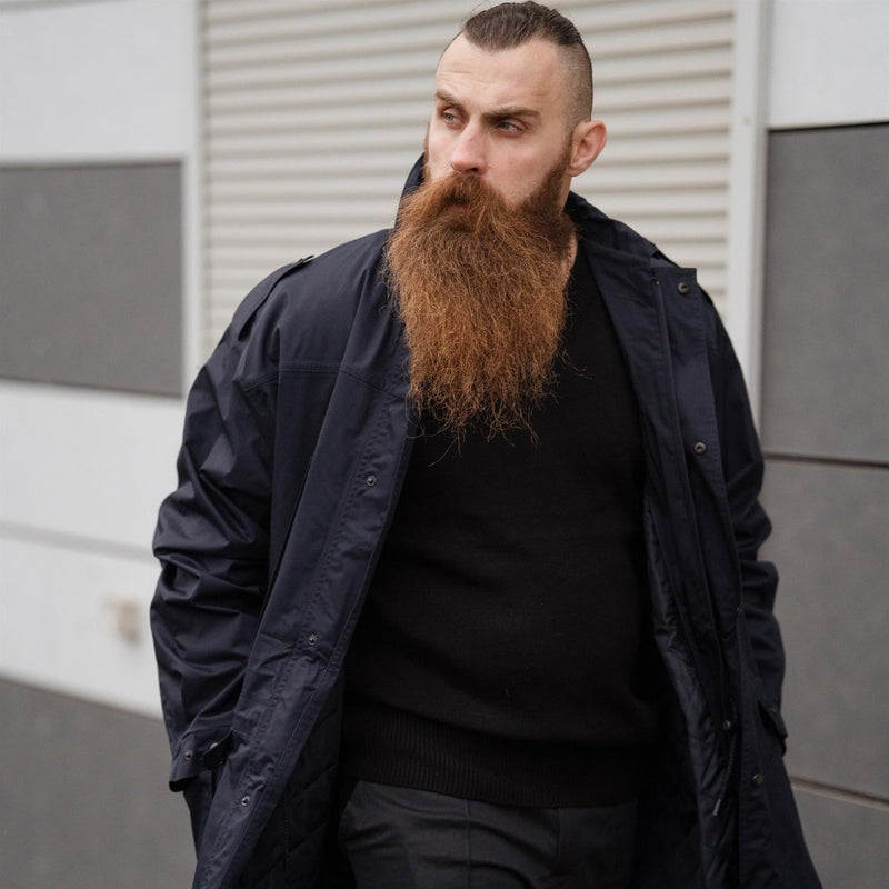 Man wearing a dark blue original Dutch police issue military surplus parka jacket with a hood outdoors