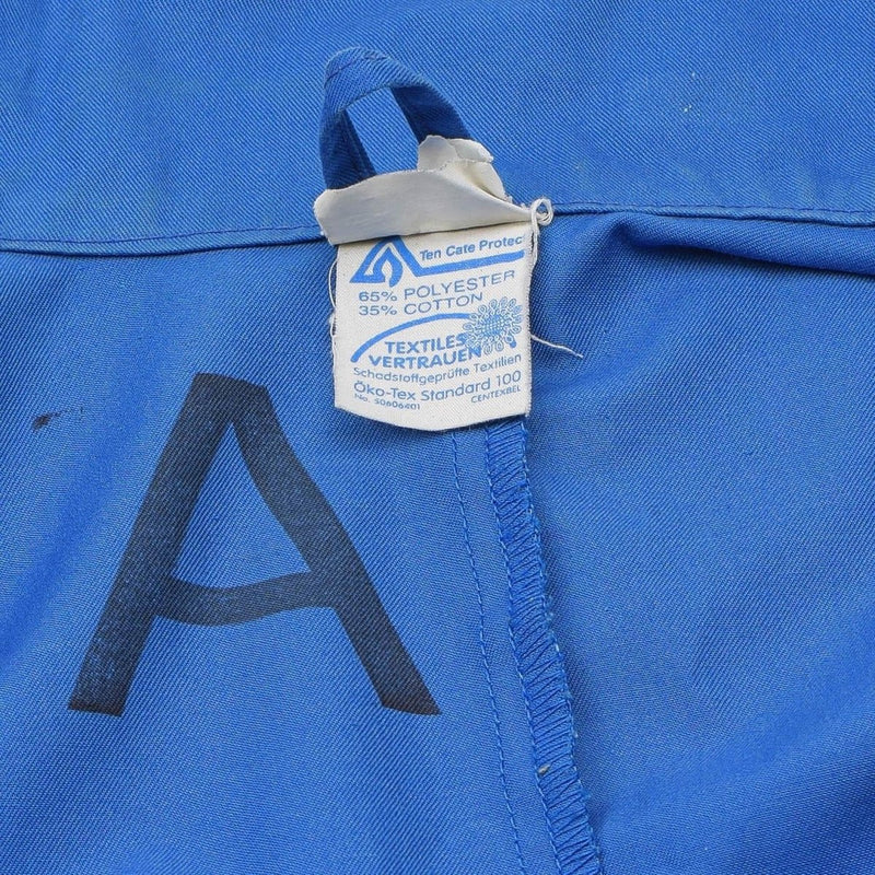 Close-up of blue Oko-Tex coverall fabric label showing 65% polyester and 35% cotton composition with sewn seam details.