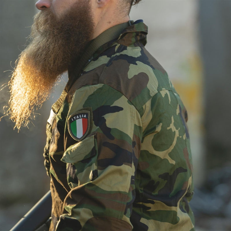 Side view of man wearing lightweight woodland camo Italian military combat jacket with Italia patch on arm