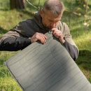 Man inflating an olive green lightweight U.S. military Therm-A-Rest self-inflating sleeping pad outdoors