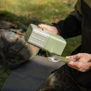 Person holding original Yugoslavian military mess kit and cutlery outdoors on camouflage pants background
