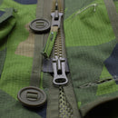 Close-up of green splinter camo TACGEAR military commando smock jacket with YKK zipper, buttons, and ripstop fabric details